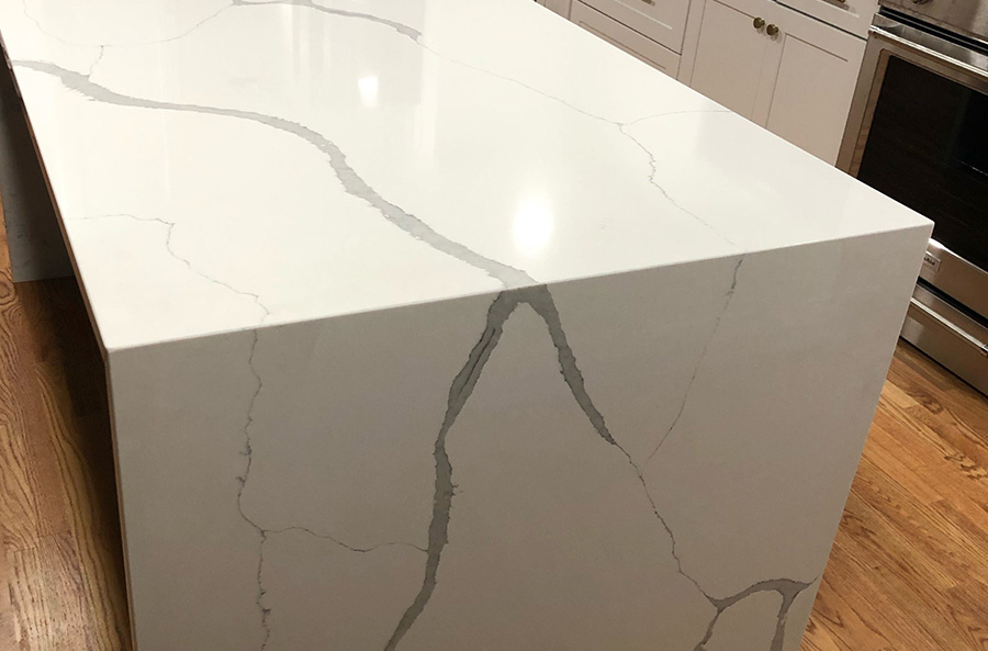 Recently Installed White Quartz Kitchen Island Waterfall Features Creamy White Stone With Boldly Large Grey Veins